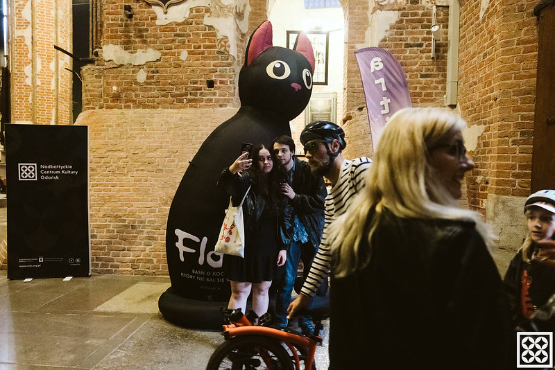 Dmuchana sylwetka kota w gotyckim wnętrzu. Ludzie robią selfie