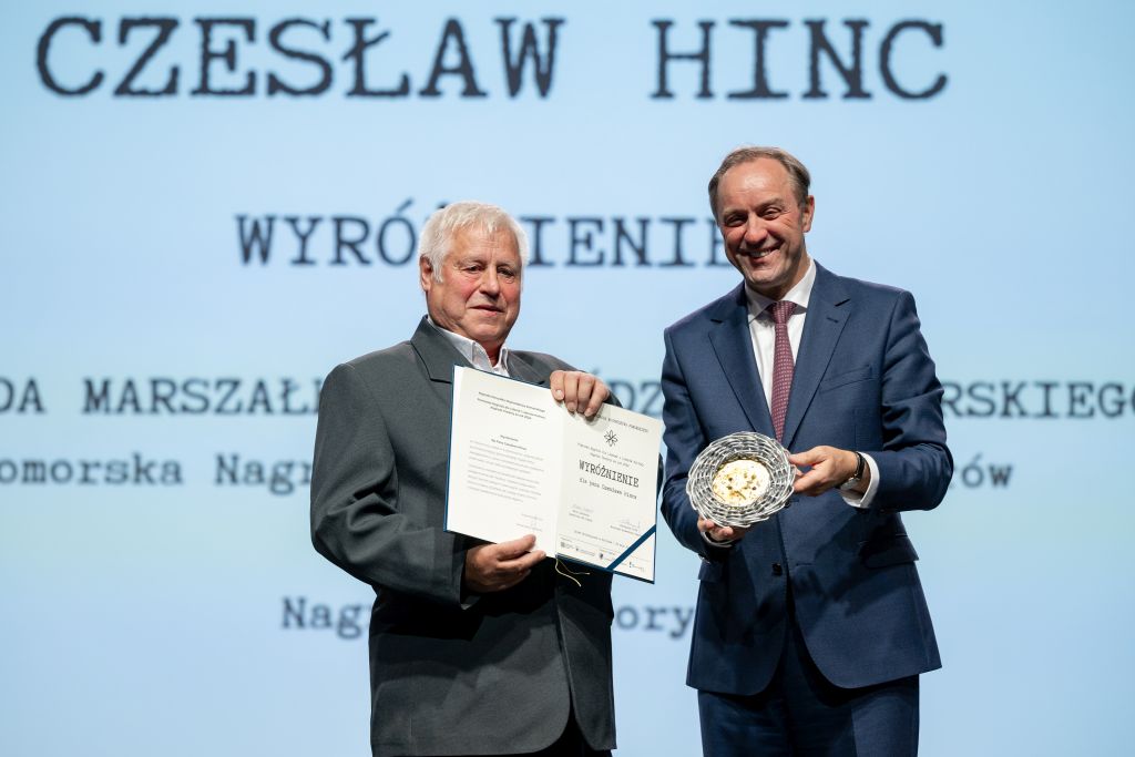 Dwie osoby na scenie. Prezentują dyplom stauetkę