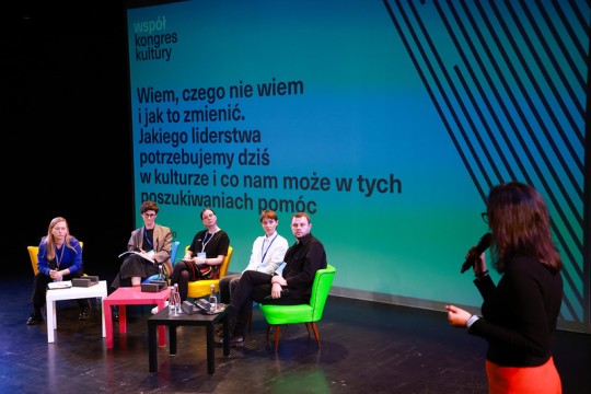 zdjęcie ludzi na scenie słuchają, debata w tle grafika z tematem rozmowy