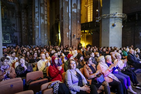 Zdjecie zabytkowego wnętrza, filary, cegły, publiczność patrzy w stronę sceny