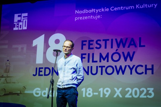 zdjęcie mężczyzny w okularach przemawiającego do mikrofonu