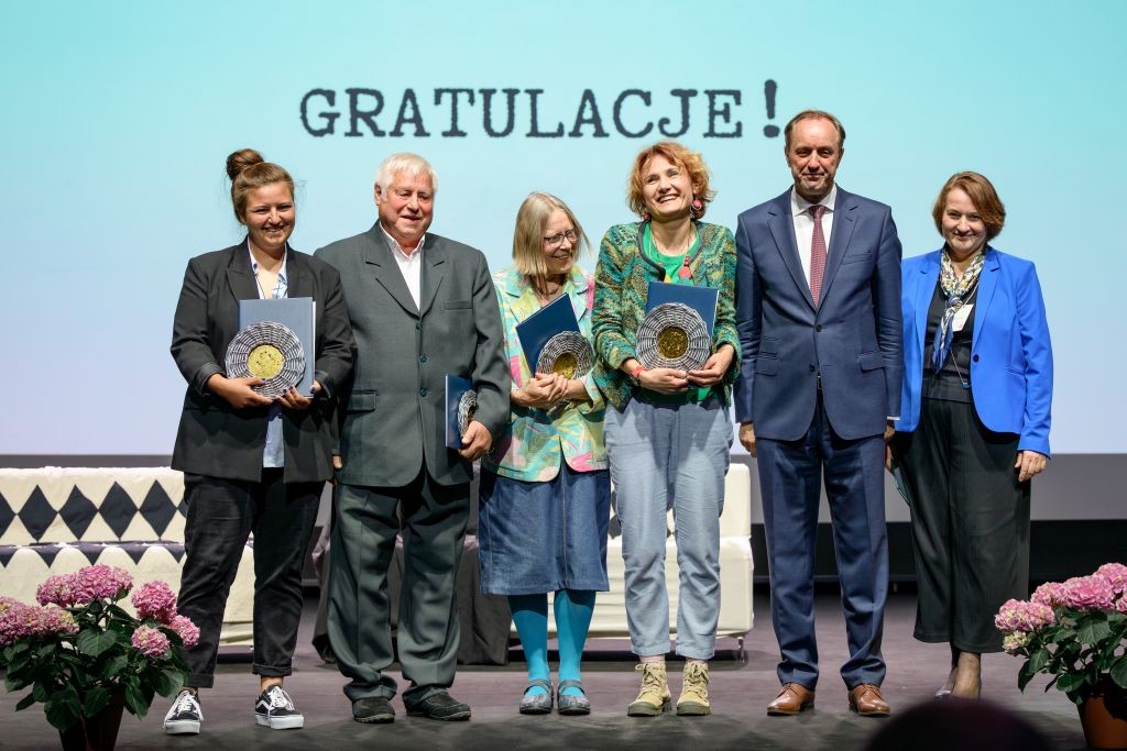 zdjęcie 6 osób na scenie 4 kobiety i jeden mężczyzna. Trzymają nagrody, w tle napis "gratulacje"