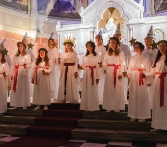 zdjęcie przedstawiające dziewczęta w białych szatach z wiankami ze świec na głowie 