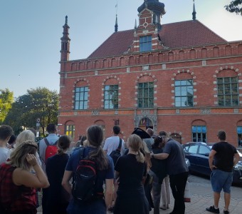 zdjęcie na zewnątrz, ludzie przyglądają się zabytkowemu budynkowi Ratuszowi Saromiejskiemu