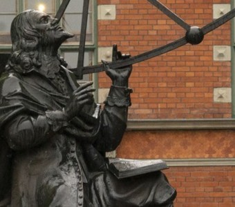zdjęcie pomnika jana Heweliusza, deszcz, w tle ceglany budynek Ratusz Staromiejski w Gdańsku